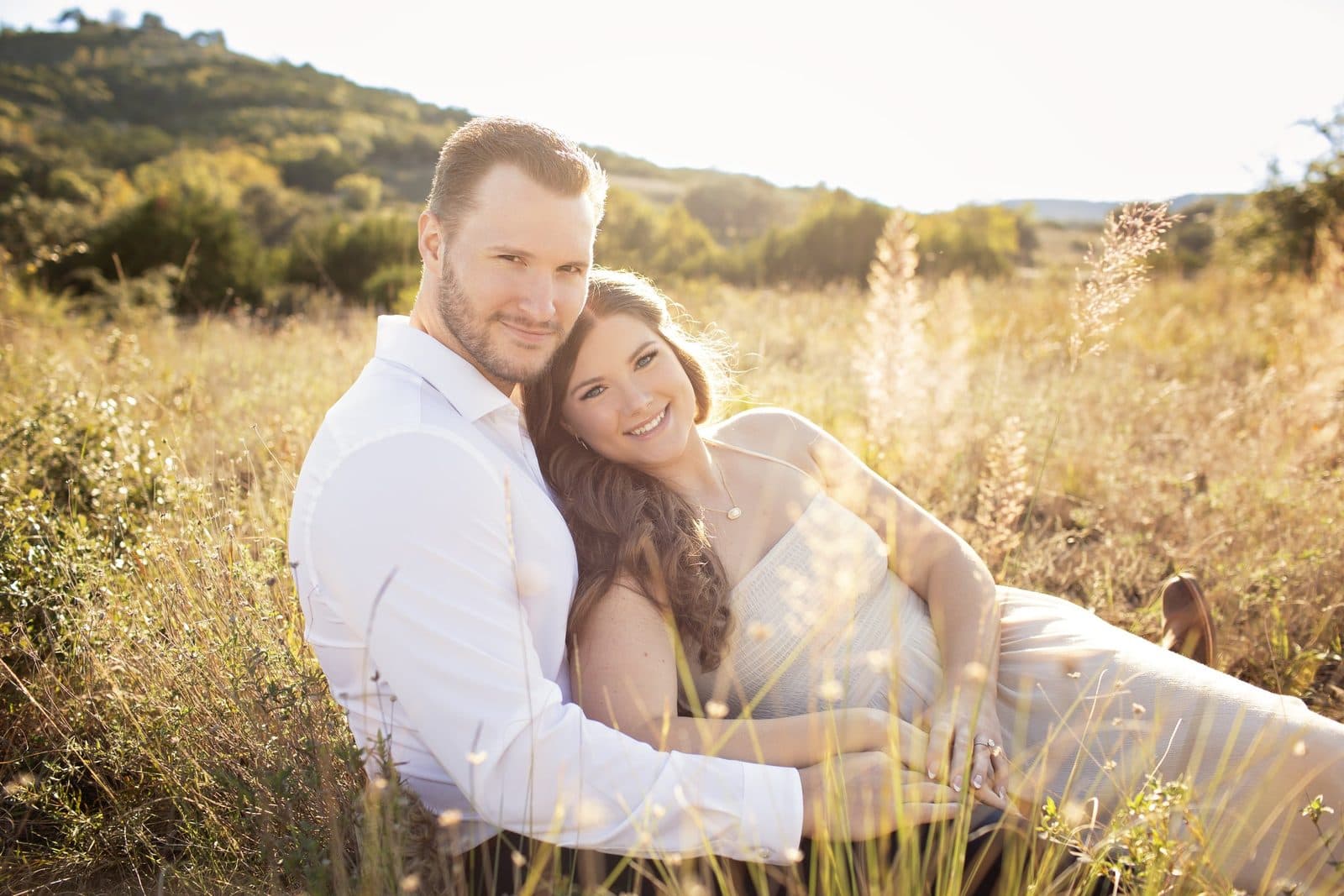 Couple seated together in a golden Texas Hill Country field at sunset