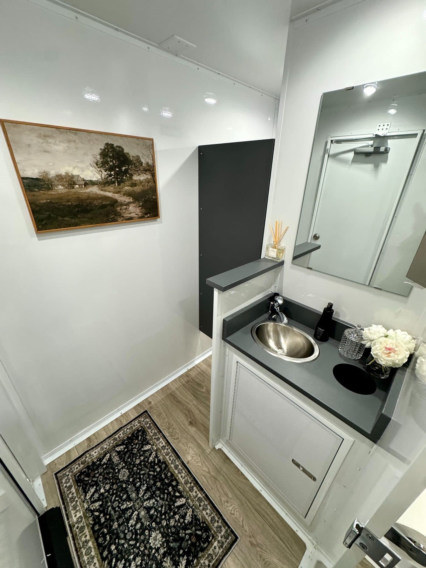 Styled vanity area inside a luxury restroom trailer with mirror, amenities tray, and warm lighting