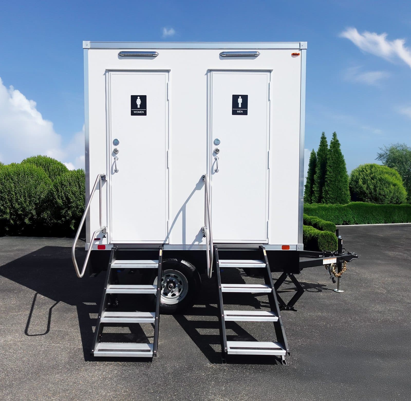 Front view of a spotless two-stall luxury restroom trailer with separate men's and women's entrances and aluminum stairs