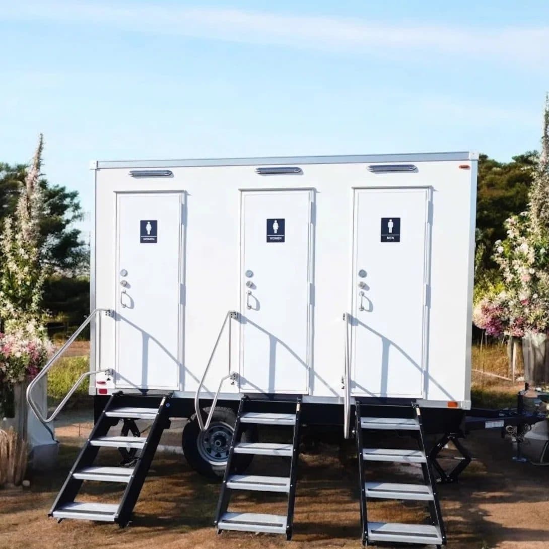 Three-station luxury restroom trailer staged with floral arrangements for an outdoor Texas wedding